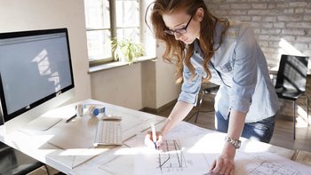 Eine Frau die in einem Buero an einem Schreibtisch steht